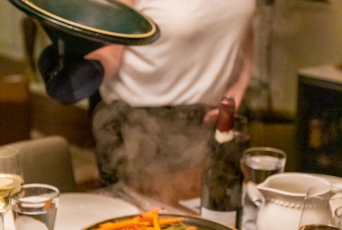 Revealing a hot, cooked meal at a dinner table in a tajine