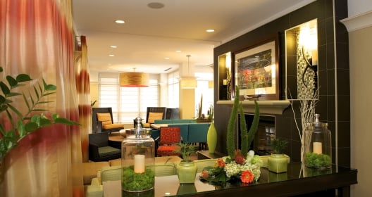 The lobby of the Hilton Garden Inn San Francisco hotel. The lobby is decorated with dark furnature and bright green plants.