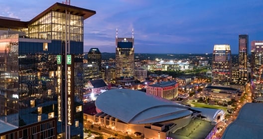 Exterior of the Embassy Suites Nashville Downtown at dusk. In the backgound is the Nashville downtown core.