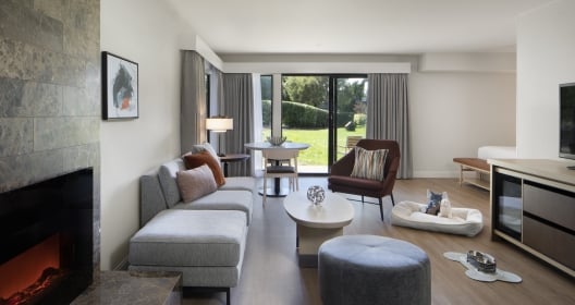 A large room area at the Hyatt Regency Monterey with a fireplace, couches and a sliding door to the outside.