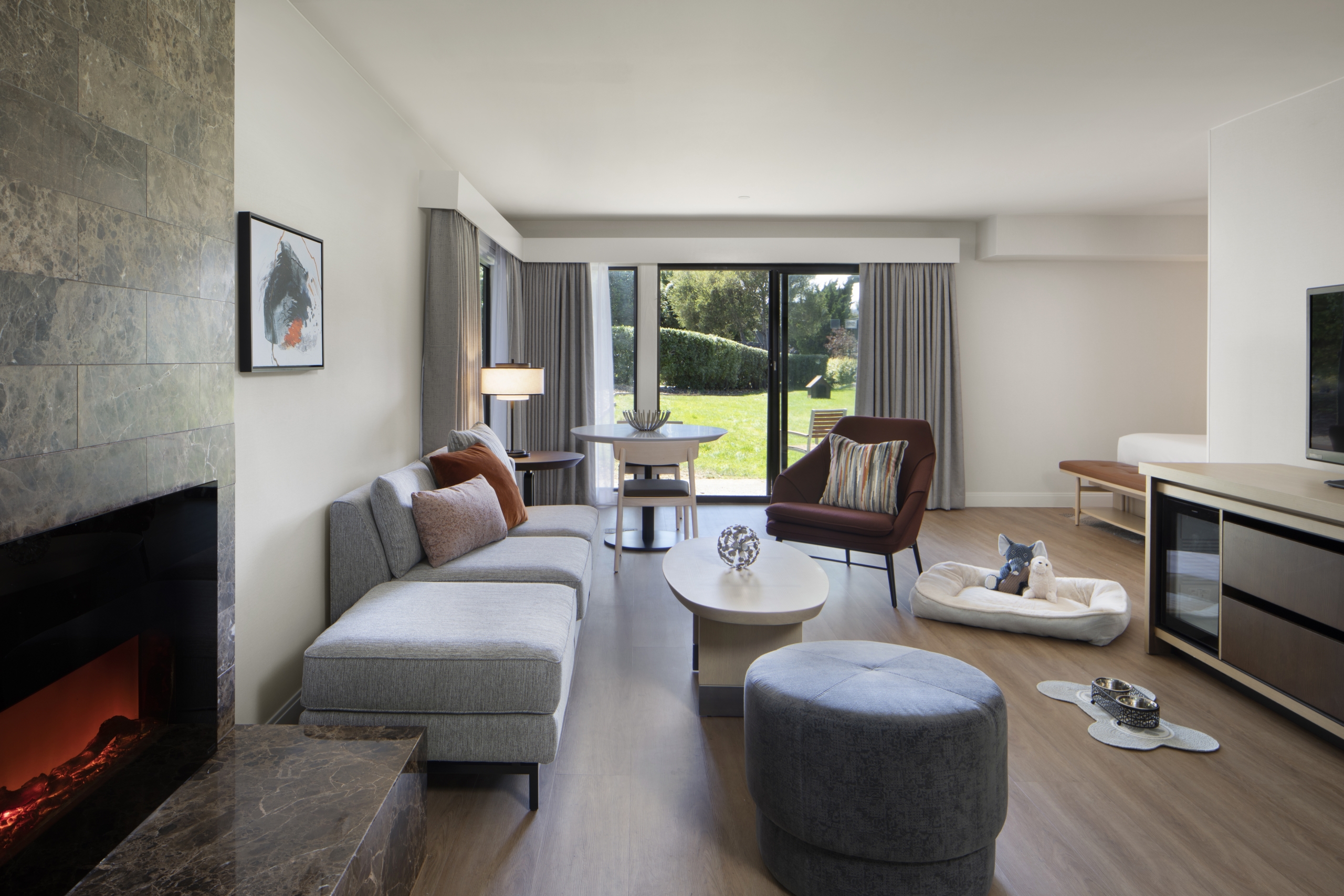 A large room area at the Hyatt Regency Monterey with a fireplace, couches and a sliding door to the outside.