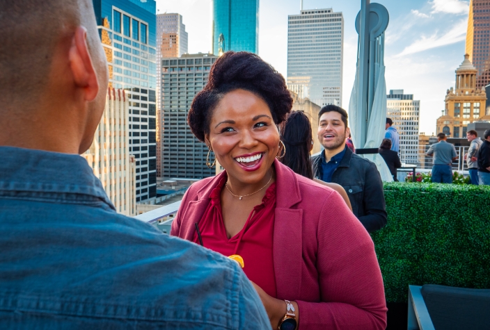 A group of individuals talking on a rooftop terrace.