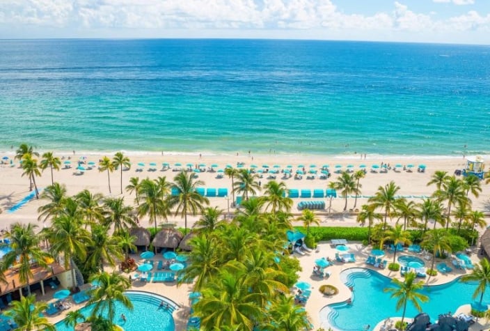 An aerial view of the beach as seen from the Margaritaville Hollywood Beach Resort hotel. In the foreground you can see two large pools.