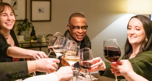 People toasting with glasses of wine over a dinner table