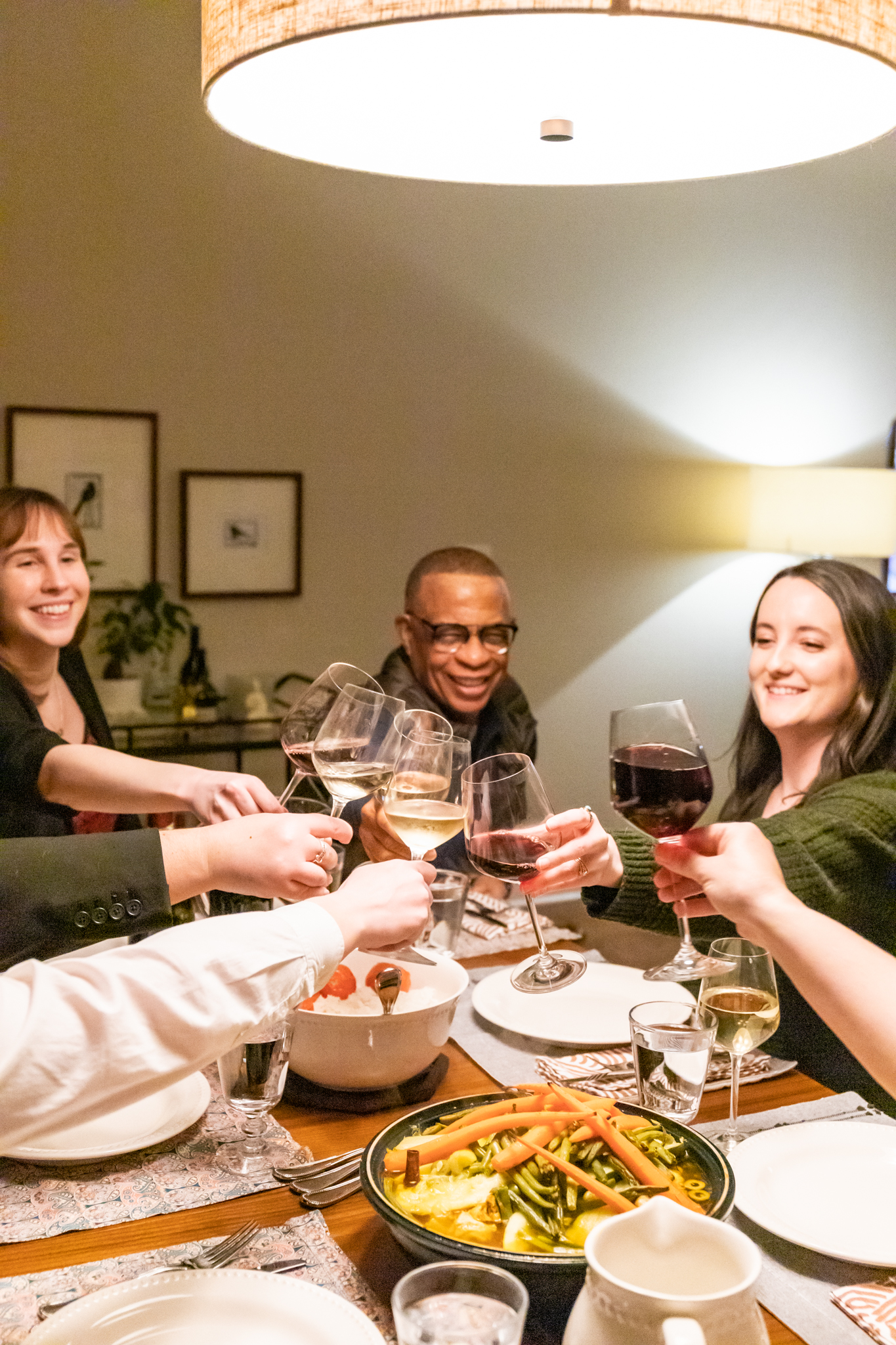 People toasting with glasses of wine over a dinner table